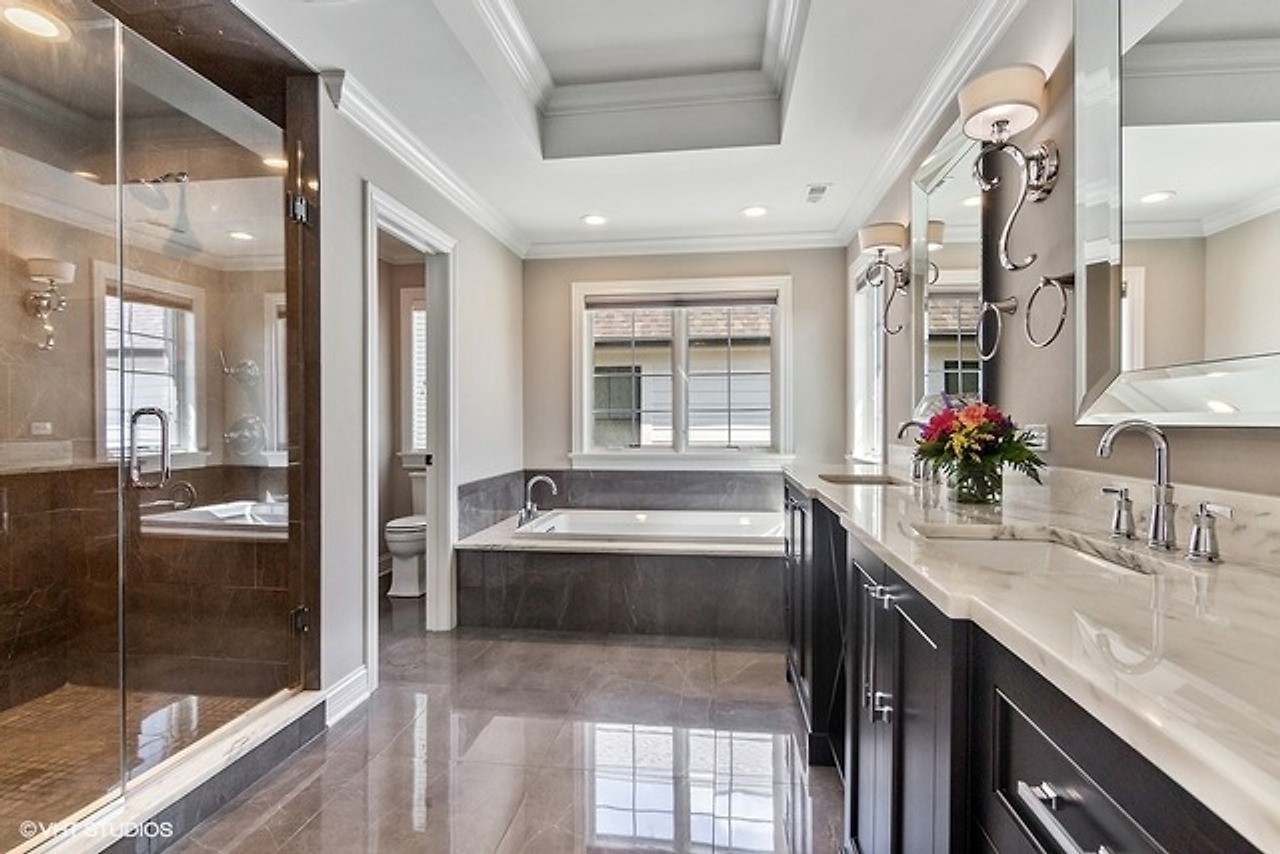 Primary bath with a marble vanity, soaking tub, and glass shower in a Gimbel Group listing